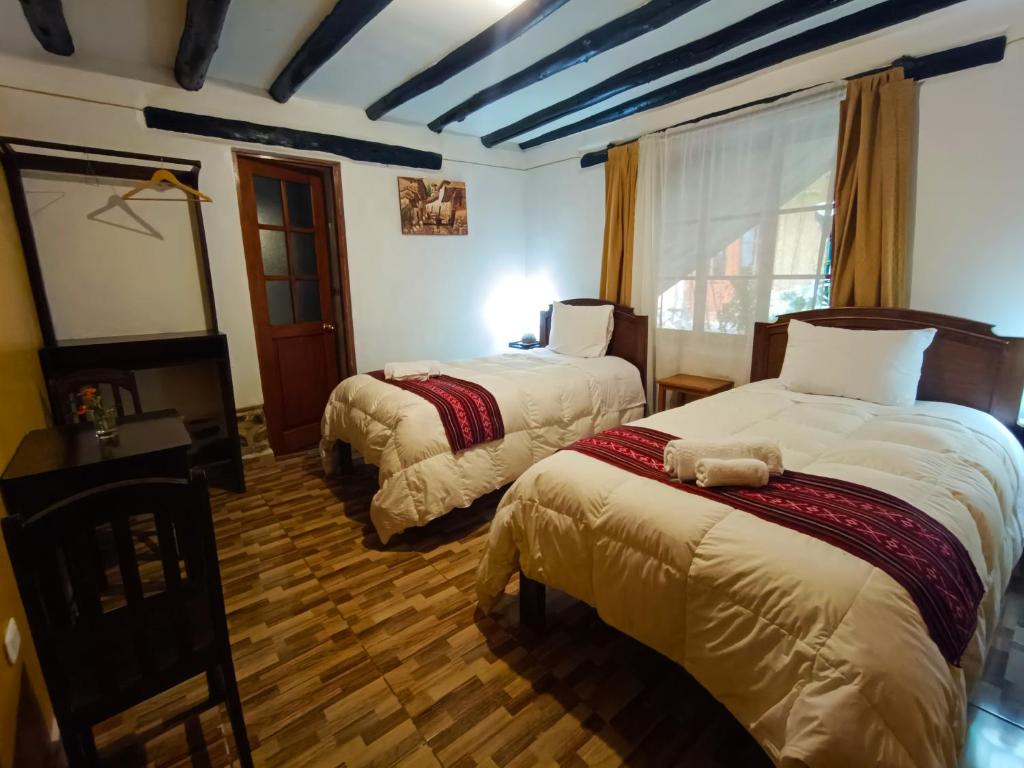 Wayras Hostal في أولانتايتامبو: غرفة فندقية بسريرين ونافذة