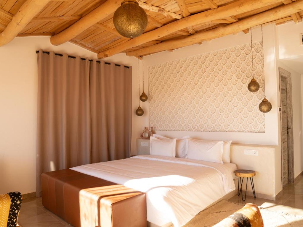 1 dormitorio con 1 cama grande y techo de madera en Sahara pearl Hotel en Merzouga