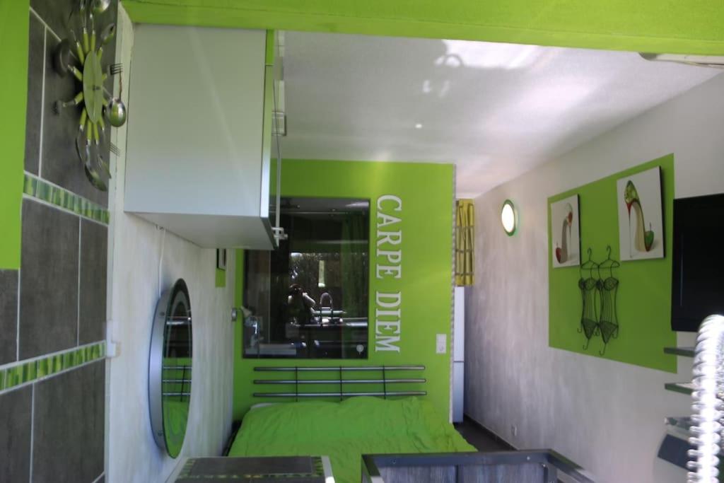Cette chambre verte et blanche dispose d'un lit et d'un miroir. dans l'établissement Studio 6, Port Nature 1 au village naturiste, au Cap d'Agde