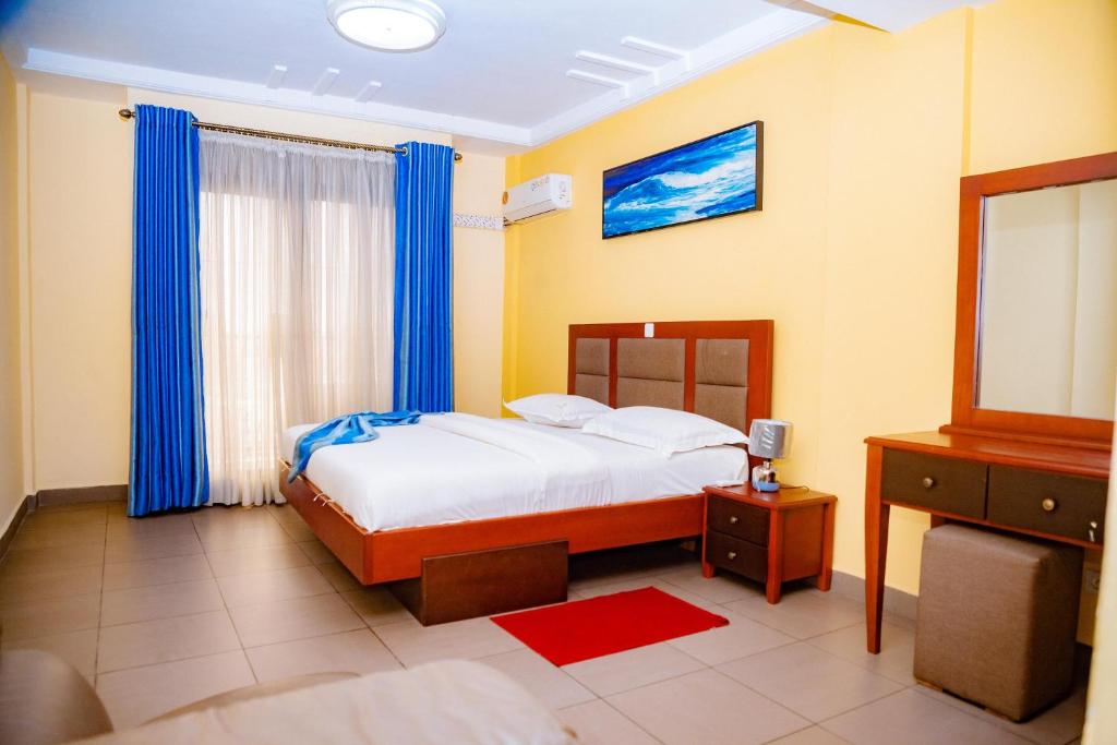 een slaapkamer met een bed met blauwe gordijnen en een spiegel bij RESIDENCE BELMANN in Douala