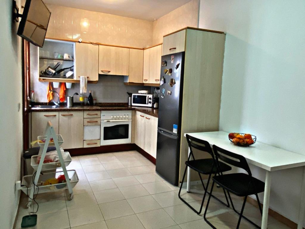 eine Küche mit einem Kühlschrank sowie einem Tisch und Stühlen in der Unterkunft Amanecer Isleño Habitaciones in Arrecife