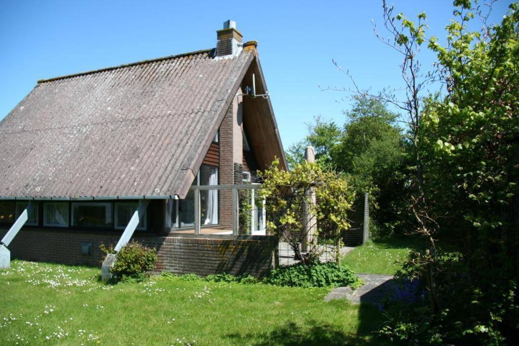 uma casa com um telhado castanho num jardim verde em De Vlier 25* em Nieuwvliet