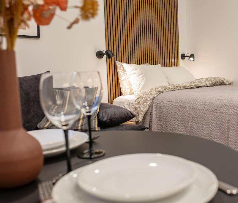 einen Tisch mit zwei Weingläsern und einem Bett in der Unterkunft Modern Riverside Stays for 4 in Vilnius