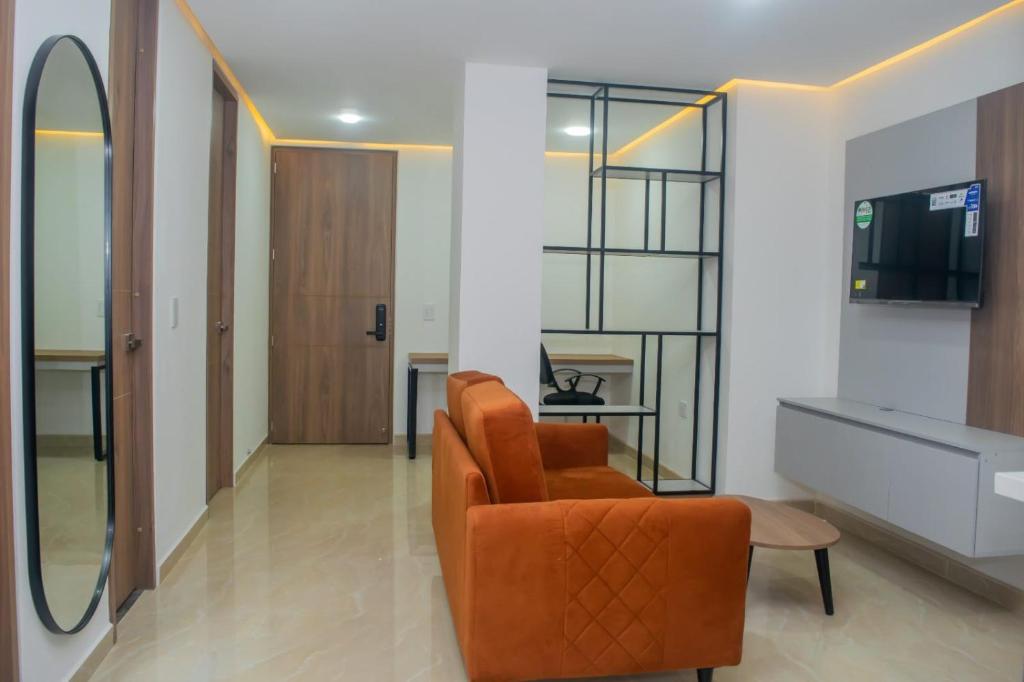 uma sala de estar com uma cadeira laranja e uma televisão em Mar Apartamentos em Bucaramanga