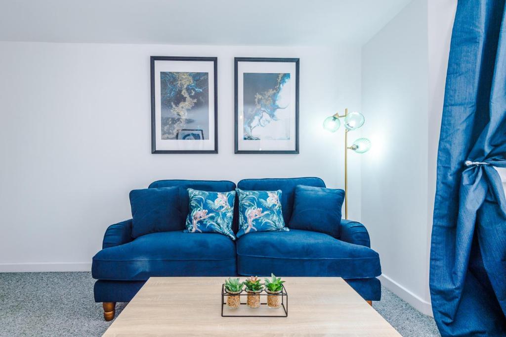 a blue couch in a living room with a table at The Consort Serviced Apartment Coventry in Coventry