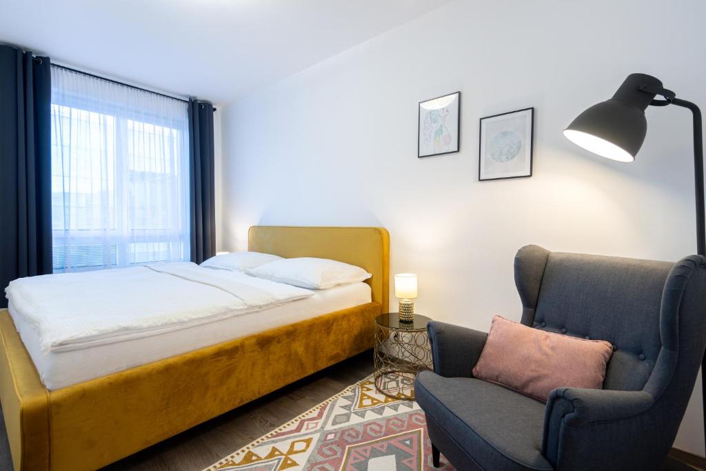 een slaapkamer met een bed, een stoel en een lamp bij Nova Karolina Apartment in Moravská Ostrava