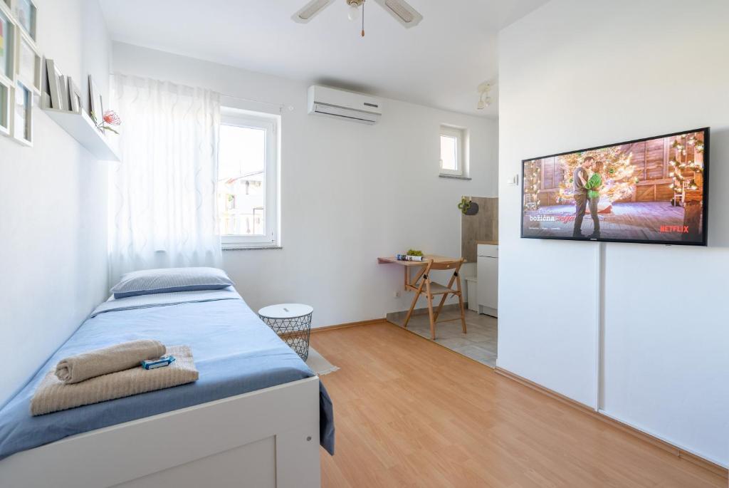 a bedroom with a bed and a tv on a wall at Sunny & Cosy Studio wParking in Rovinj