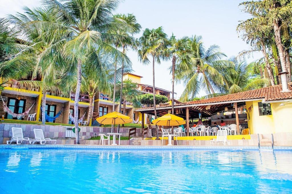 - une piscine dans un complexe avec des chaises et des parasols dans l'établissement Hotel Tubarão, à Natal