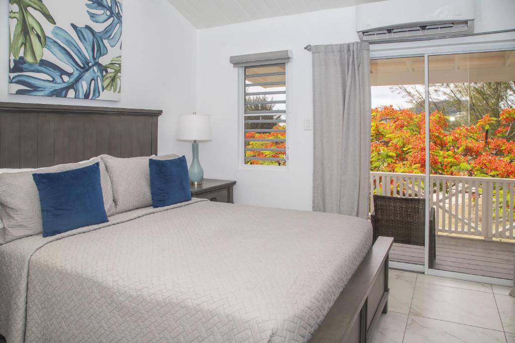 a bedroom with a bed with blue pillows and a window at 101H Jolly Harbour, Garden View in Jolly Harbour