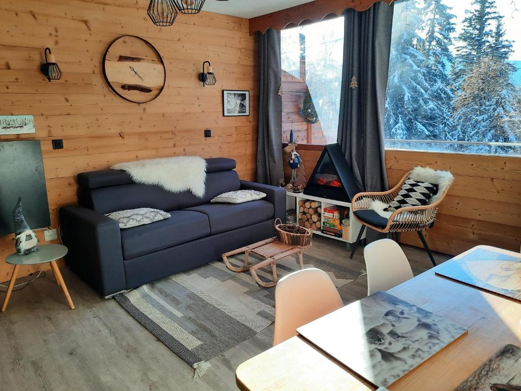 ein Wohnzimmer mit einem blauen Sofa und einem Tisch in der Unterkunft La Petite Foret Chamrousse 1700 in Chamrousse