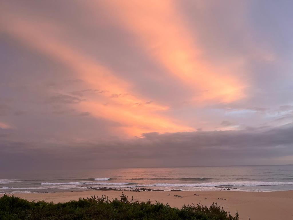 a rainbow in the sky over a beach at The Unexpected at Cannon Rocks in Cannon Rocks