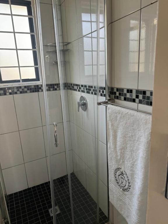 a bathroom with a glass shower with a towel at 389b Beautiful Bachelor Cottage in Johannesburg