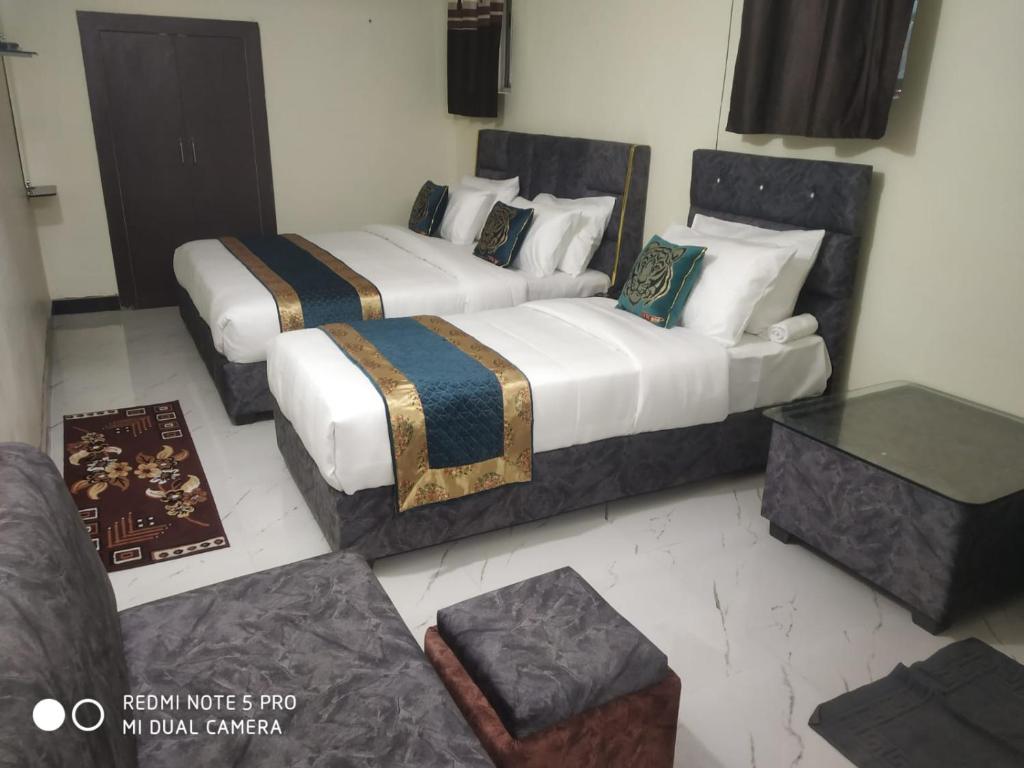 two beds in a room with a couch at Hotel Kumkum Chhaya in Panna