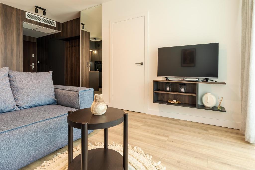 ein Wohnzimmer mit einem blauen Sofa und einem TV in der Unterkunft RentPlanet - Kras Resort in Szklarska Poręba