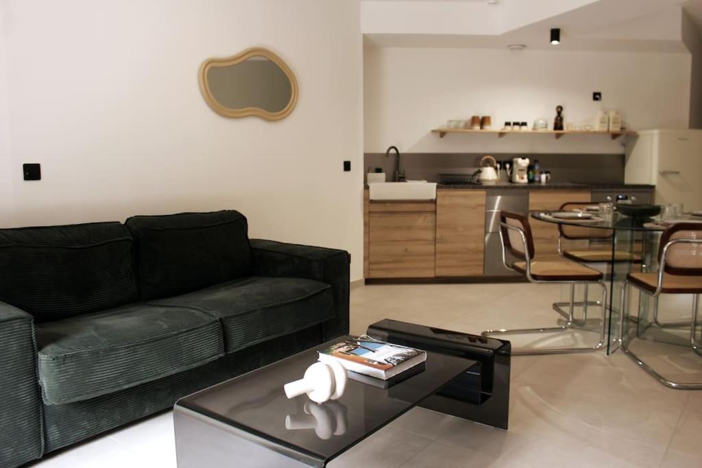 ein Wohnzimmer mit einem schwarzen Sofa und einem Tisch in der Unterkunft Superbe Appartement avec Clim/Terrasse/Parking in Montpellier
