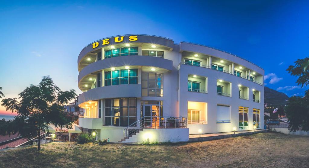 a large white building with a sign on it at Apartments Deus in Dobra Voda