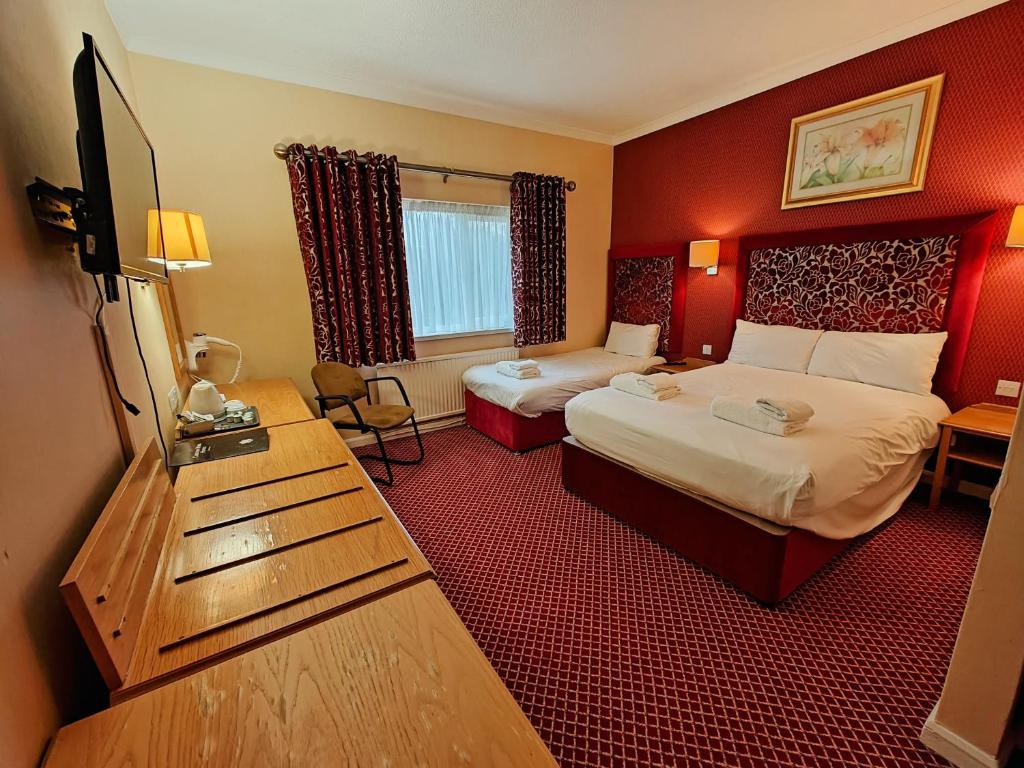 a hotel room with two beds and a desk at Carlton Park Hotel Rotherham in Rotherham