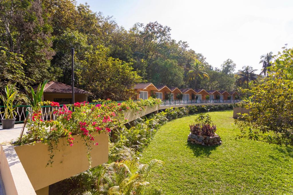 einen Garten mit einer Reihe von Häusern und Blumen in der Unterkunft Stone Wood Jungle Resort, Dandeli in Dandeli