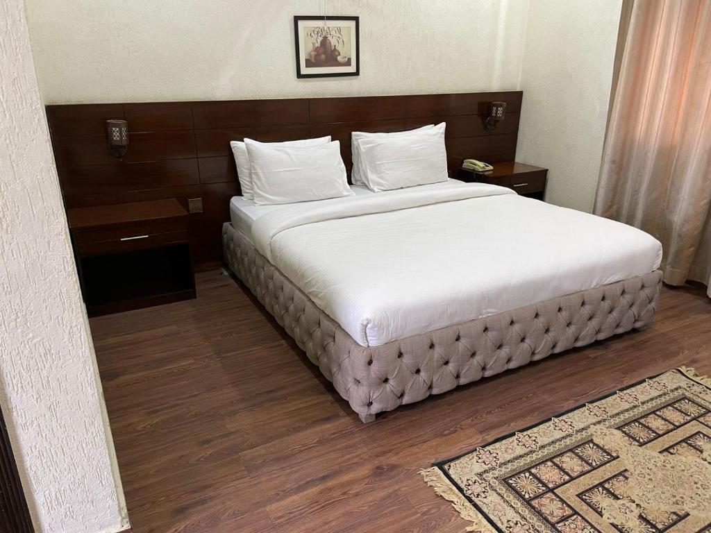 una camera da letto con un grande letto con lenzuola bianche di Hotel Crescent a Tahkāl Pāyān