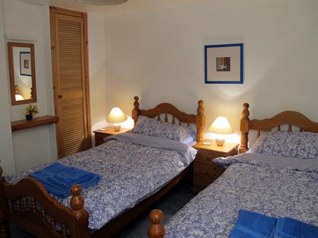 2 camas num quarto com 2 candeeiros nas mesas em Fisherman's Cottage em Tobermory