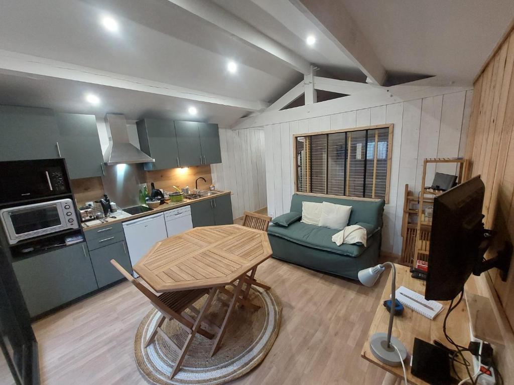 ein Wohnzimmer mit einem blauen Sofa und einer Küche in der Unterkunft La Cabane 14 in Lanton