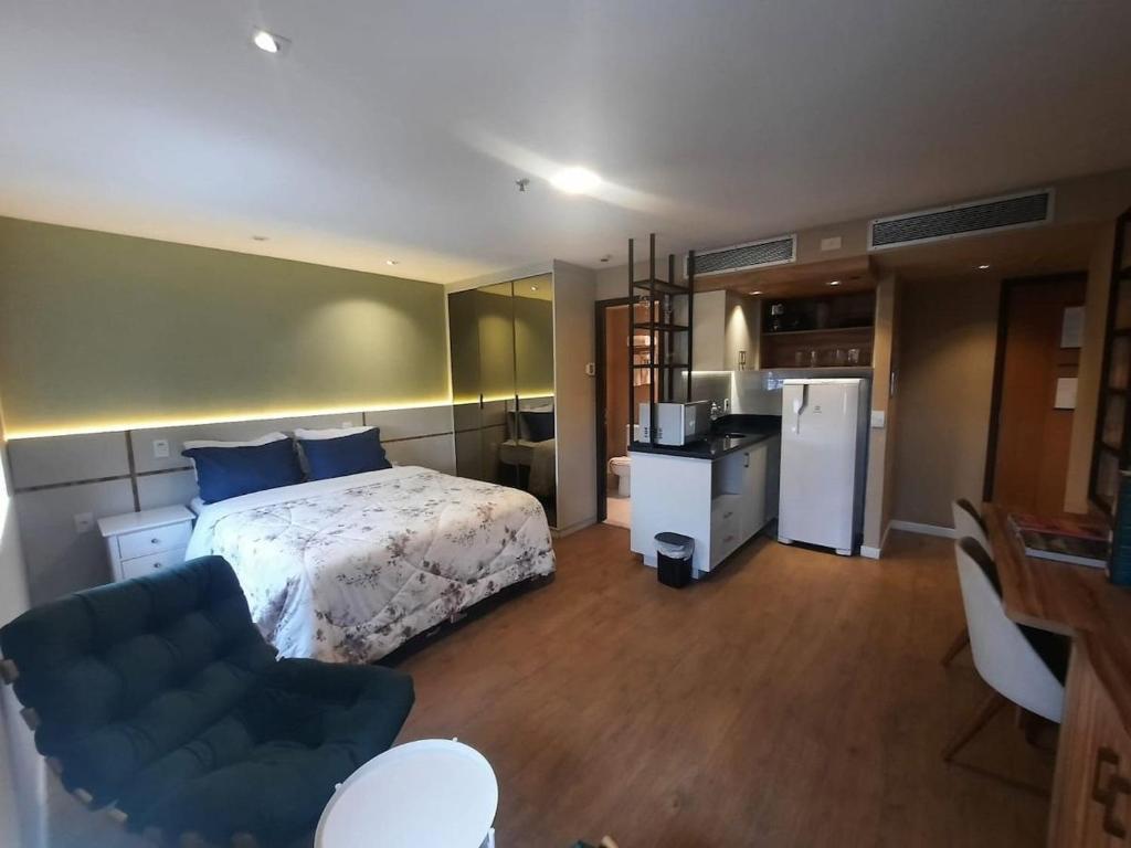 a bedroom with a bed and a couch and a kitchen at FLAT HOTEL DOIS QUARTOS AV IBIRAPUERA 2927 in Sao Paulo