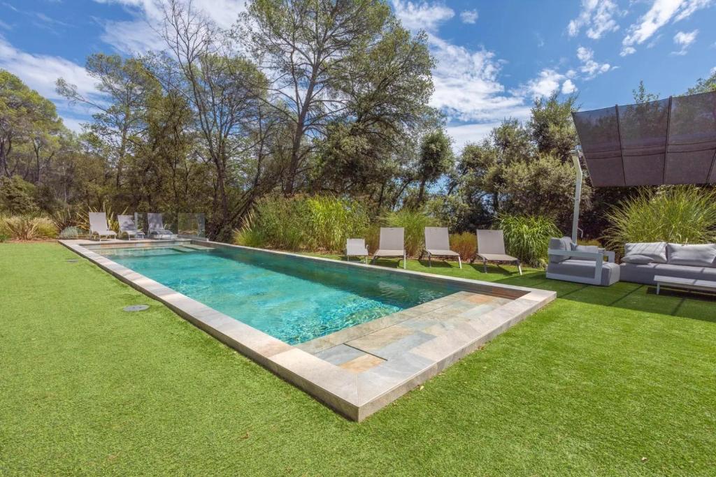- une piscine dans une cour avec des chaises et une pelouse dans l'établissement Grand Appartement Valeriane, à Trans-en-Provence