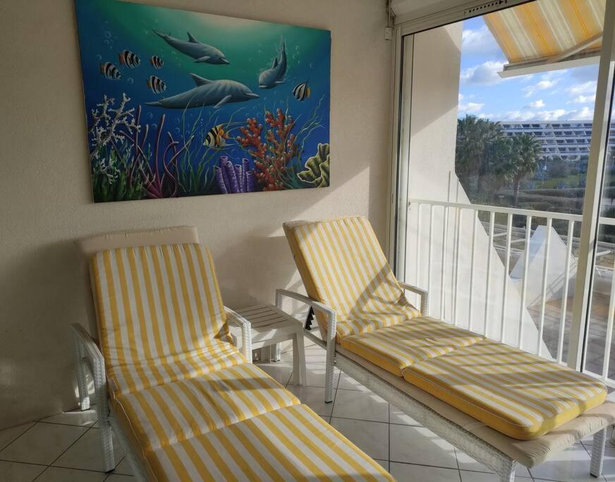 a balcony with two chairs and a painting on the wall at Appartement 204, Natura Beach au village naturiste in Cap d'Agde