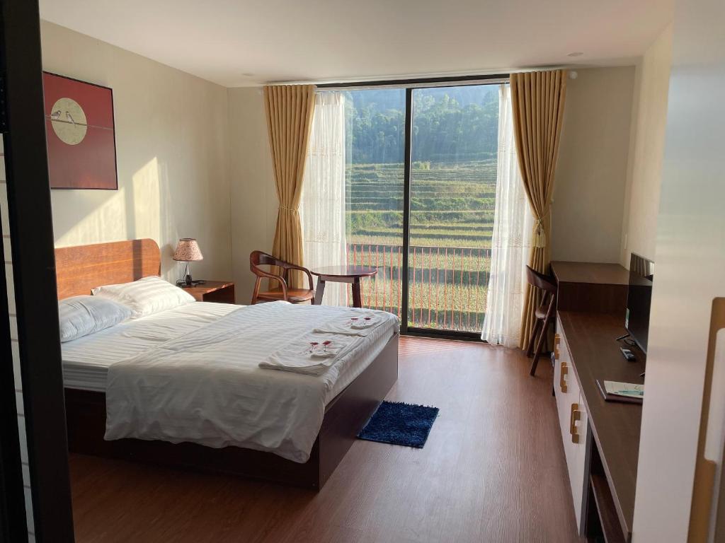 um quarto com uma cama e uma grande janela em Aurora's House em Dong Van