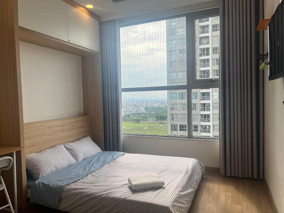 - une chambre avec un lit et une grande fenêtre dans l'établissement VINHOMES GARDENIA, à Hanoï