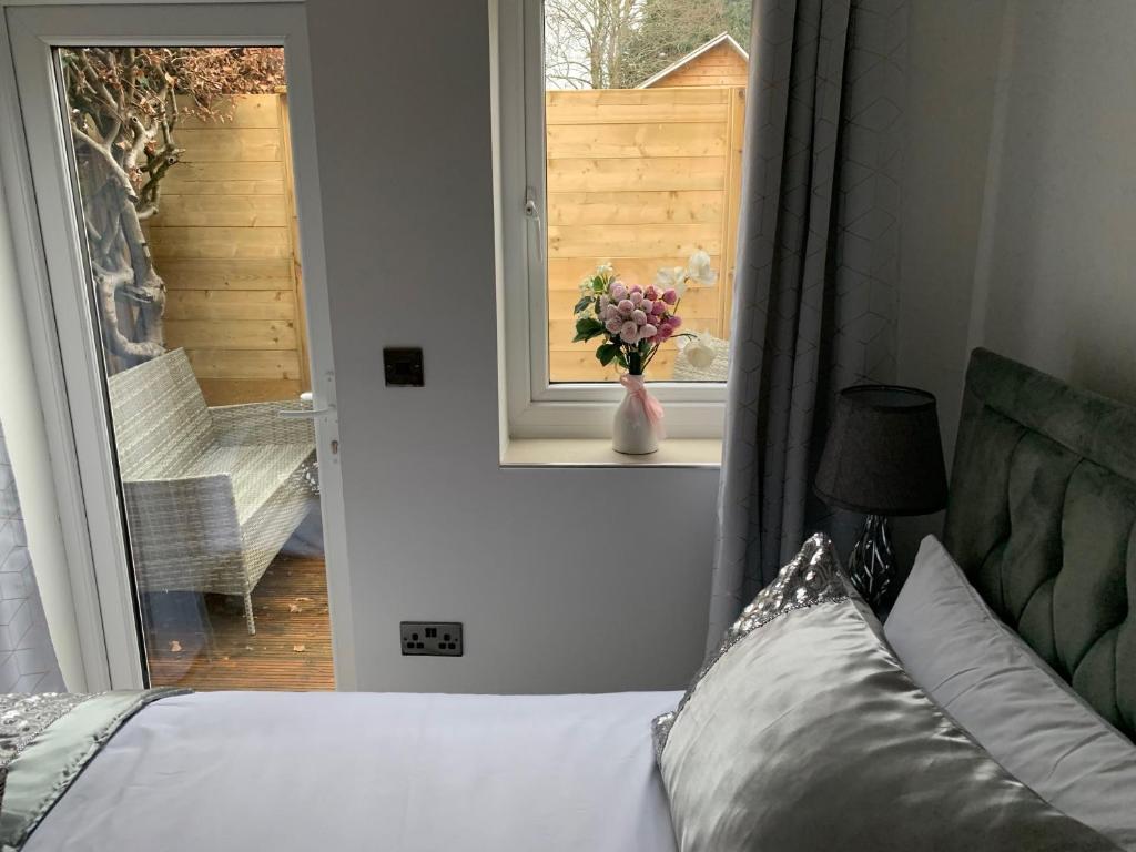Un dormitorio con una cama y un jarrón de flores en una ventana en Annex A, a one bedroom Flat in south London, en Carshalton
