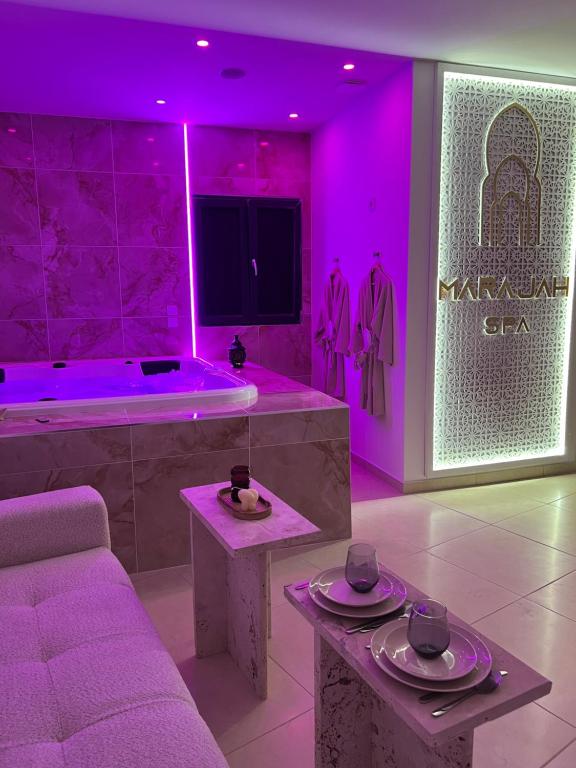 een paarse kamer met een bank en een bad met een tv bij Suite Marajah in Le Pontet