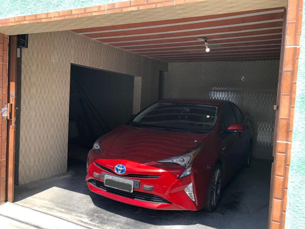 czerwony samochód stoi w garażu w obiekcie CASA DE FÉRIAS BH w mieście Belo Horizonte