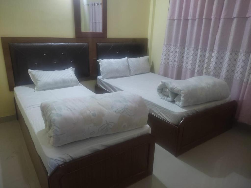 Habitación con 2 camas y un gato durmiendo en ellas en Hotel aradhya en Lumbini