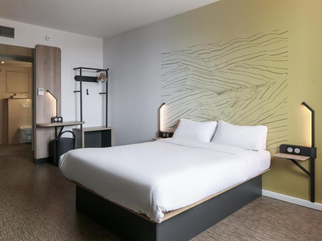 マルセイユにあるB&B HOTEL Marseille Prado Vélodromeの壁付きの客室の大きな白いベッド1台