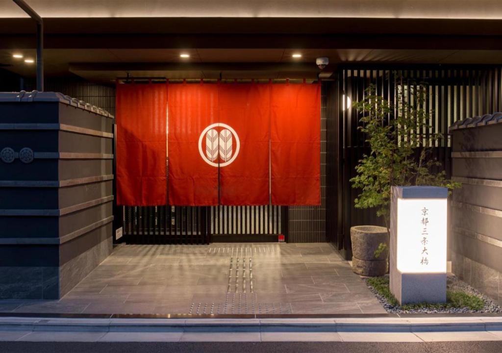 a red gate with a sign in front of a building at Kyoto Sanjo Ohashi in Kyoto