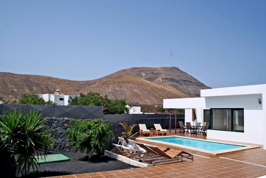 uma villa com piscina e montanhas ao fundo em Villa Andy Lanzarote em Yaiza