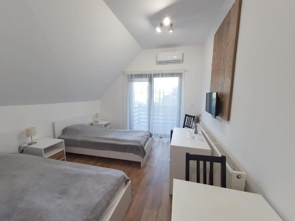 a white bedroom with a bed and a window at Double room in Pensiunea Nossa Panzió in Corunca
