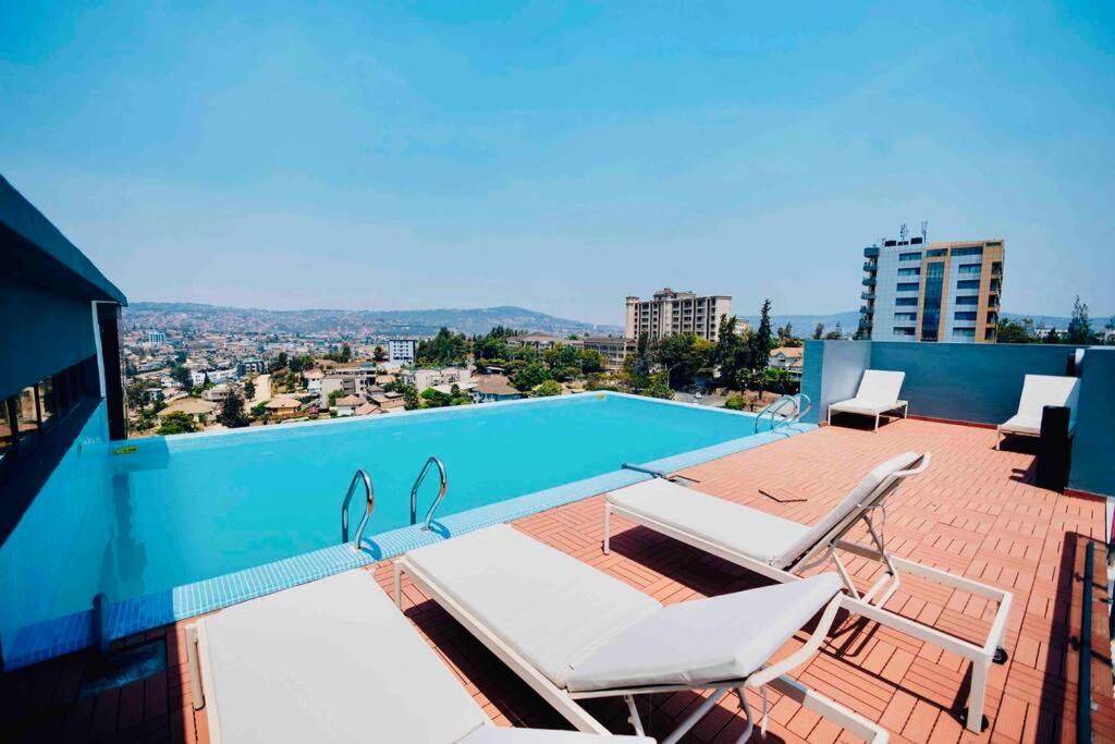 a balcony with a swimming pool and two chairs at Luxury studio apartment near Kigali Convention Center in Kigali