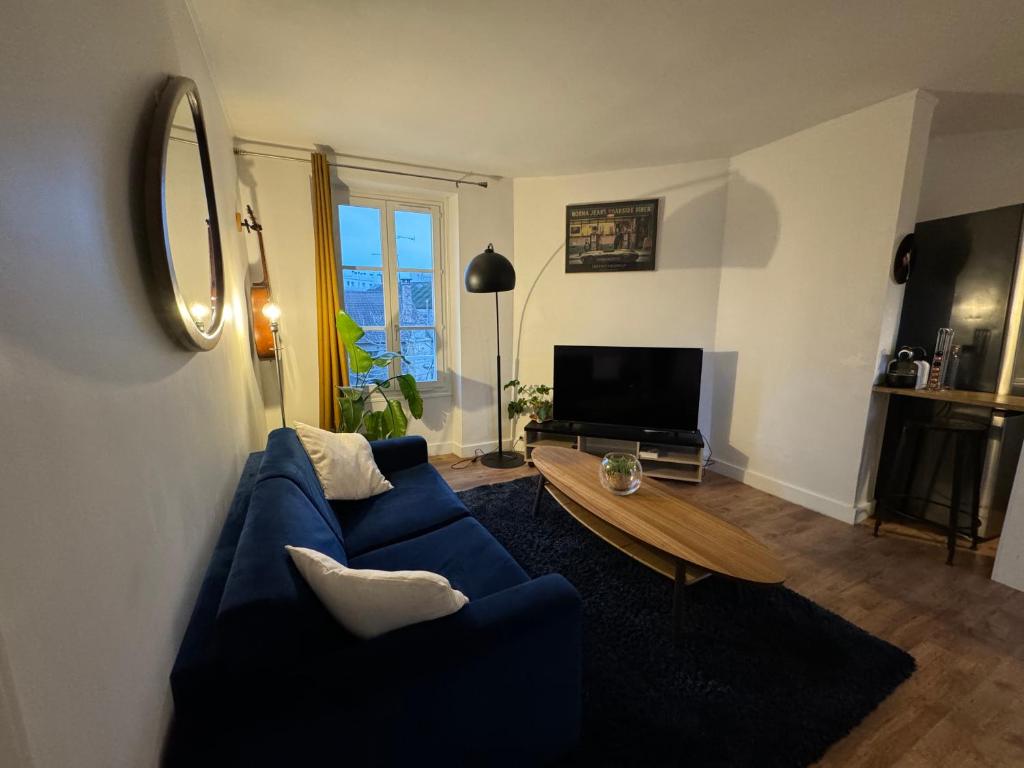 een woonkamer met een blauwe bank en een tafel bij Cosy appartement lumineux in Arcueil