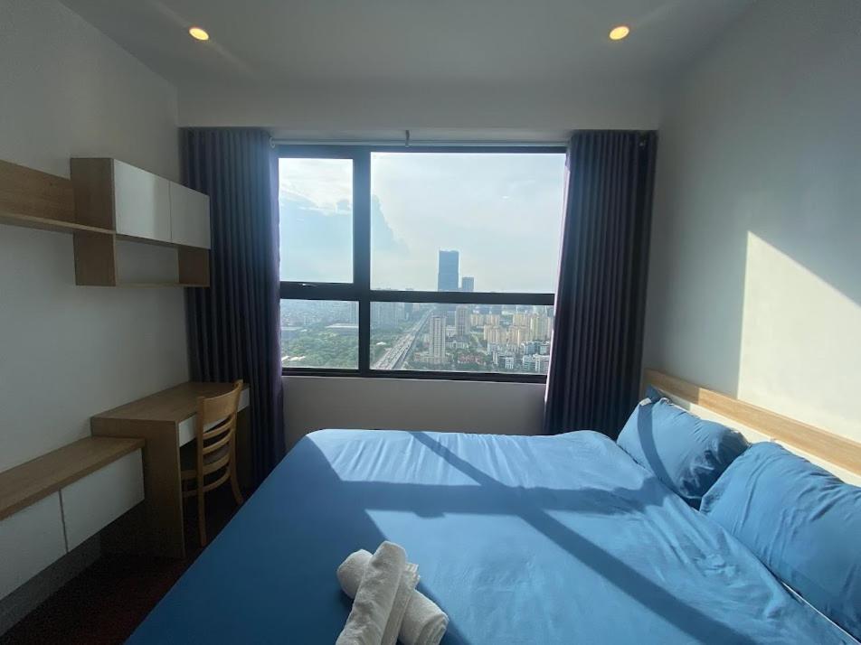 - une chambre avec un lit bleu et une grande fenêtre dans l'établissement D'CAPTIALE TRAN DUY HUNG, à Hanoï