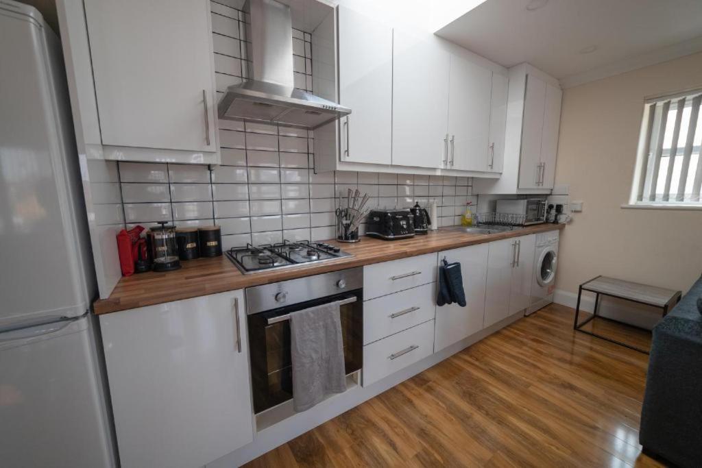 una cucina con armadietti bianchi e pavimenti in legno di Douglas's House a Dublino