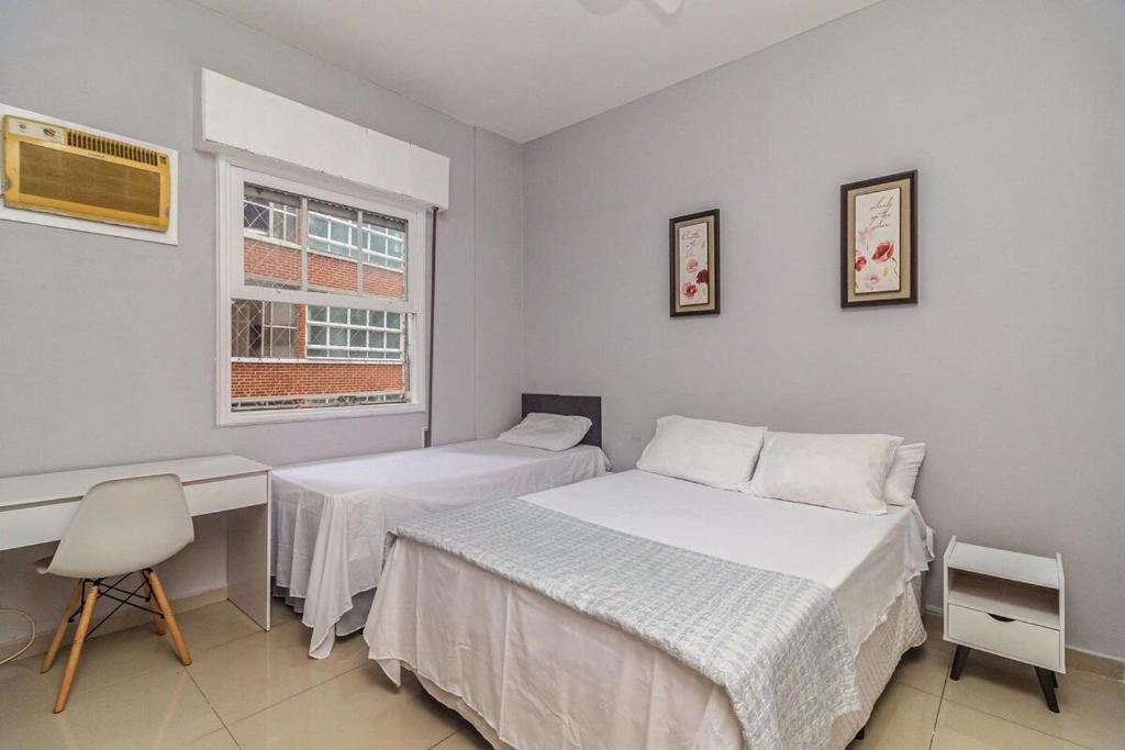 sypialnia z 2 łóżkami, biurkiem i oknem w obiekcie Apartamento a 140 metros da Praia de Santos w mieście Santos