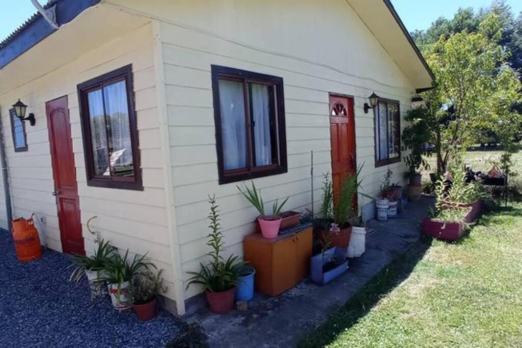 une maison avec des plantes en pot sur son côté dans l'établissement Acogedora cabaña en el campo. Cerca de la ciudad., à Villarrica