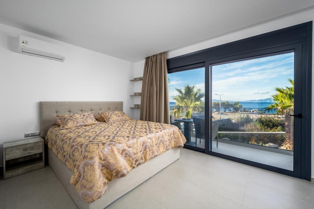 sypialnia z łóżkiem i dużym oknem w obiekcie Penélope Beachfront Villa w mieście Kremasti