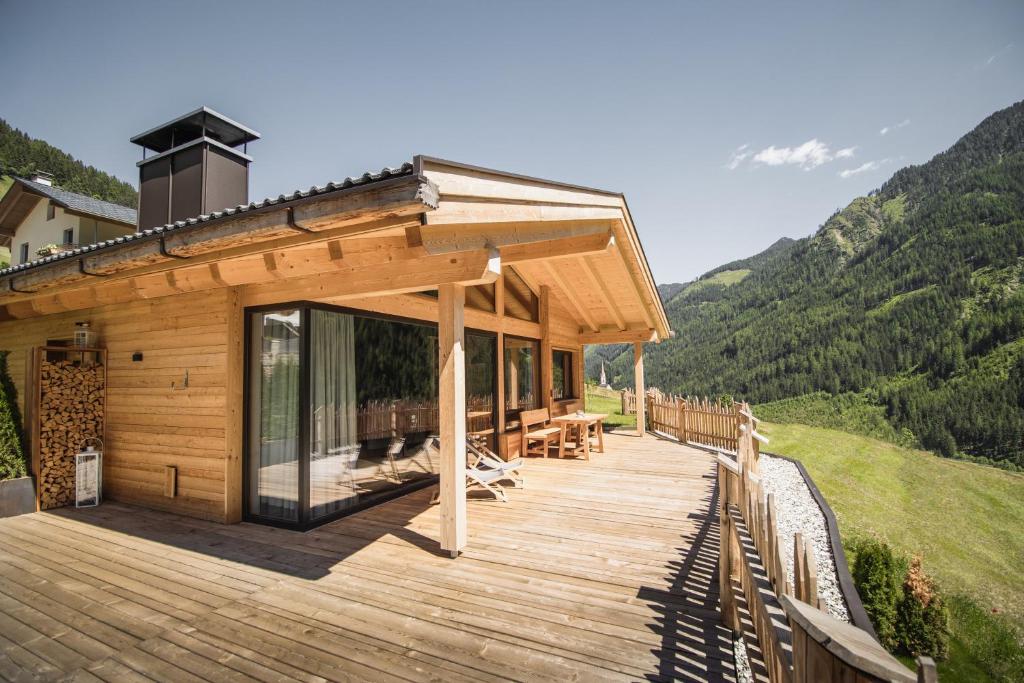 a house with a deck with mountains in the background at Chalet Berg in Selva dei Molini