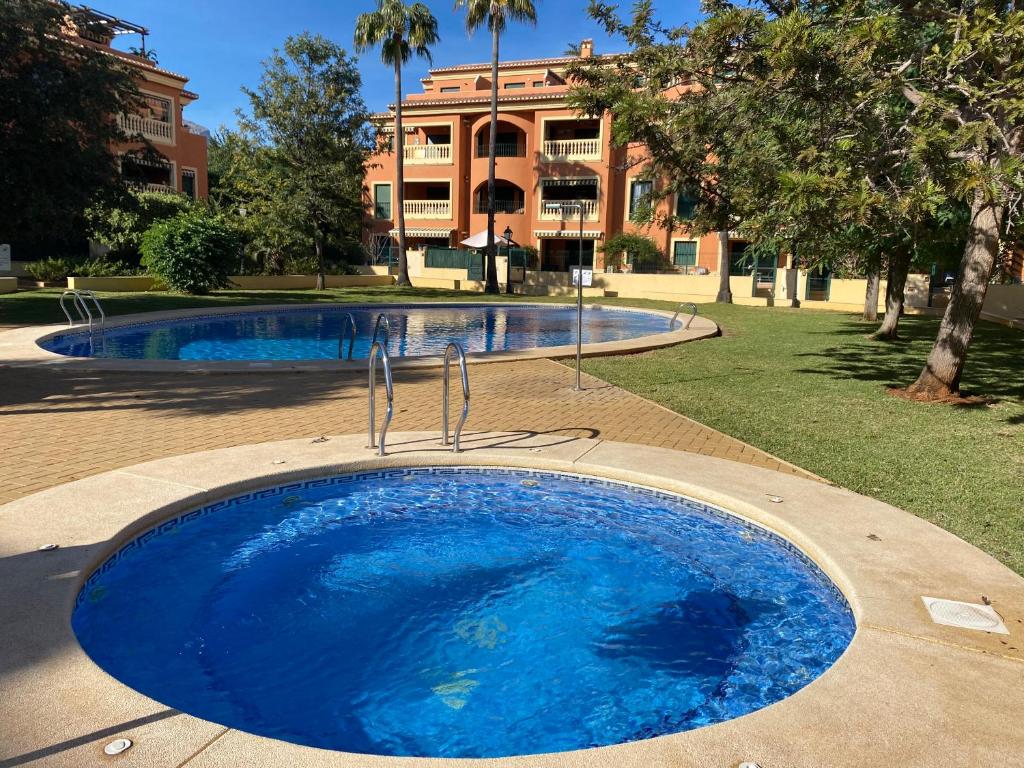 une grande piscine bleue avec un bâtiment en arrière-plan dans l'établissement La Gavina Loft Xàbia & ARCADE, à Jávea