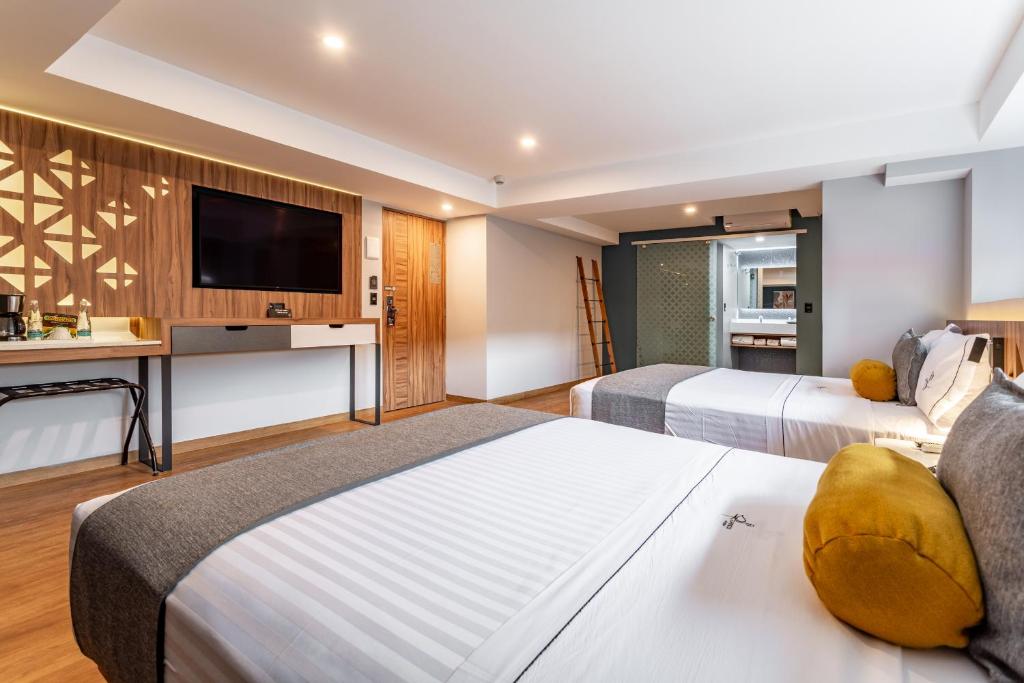 a hotel room with two beds and a flat screen tv at Hotel Flamencos in Mexico City