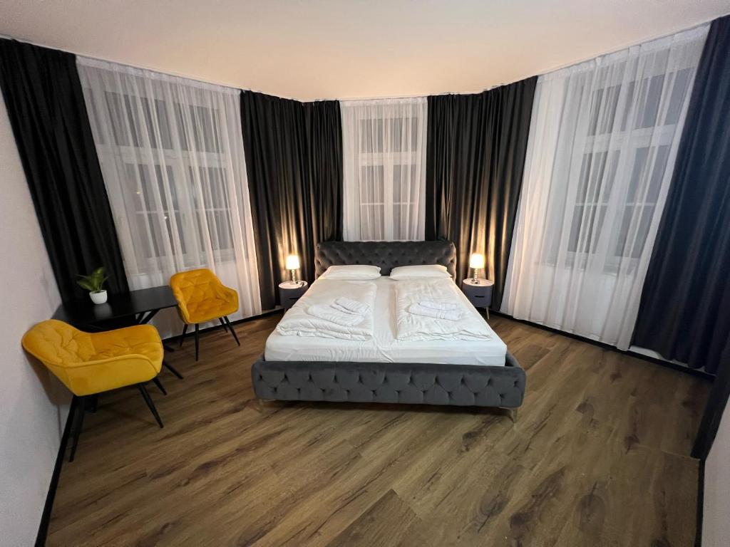 a bedroom with a bed and two yellow chairs at Hotel Elisei in Nürnberg