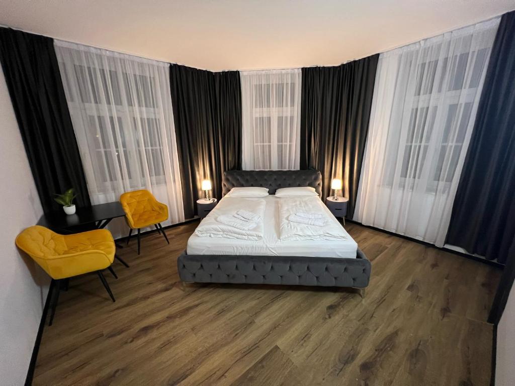 a bedroom with a bed and two yellow chairs at Hotel Elisei in Nuremberg